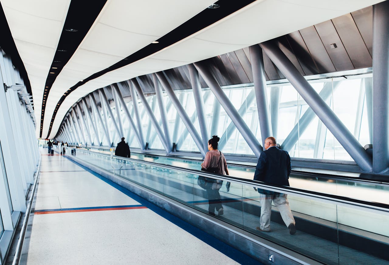 services-04 Travelers walking through a bright modern airport corridor with glass walls.